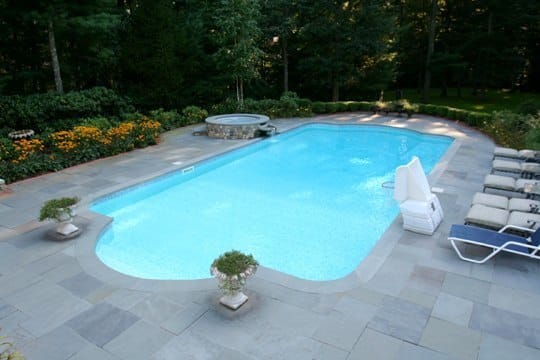 Roman inground pool in Glens Falls, NY with custom pavers, spil over hot tub and basketball hoop by Cypress Pools