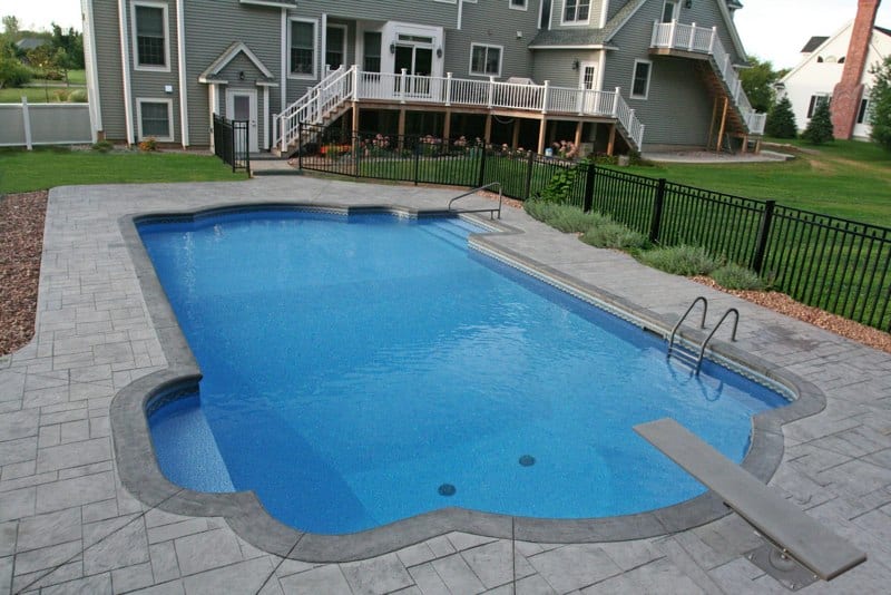Roman in ground pool in Saratoga Springs, NY with custom pavers, diving board and steps by Cypress Pools