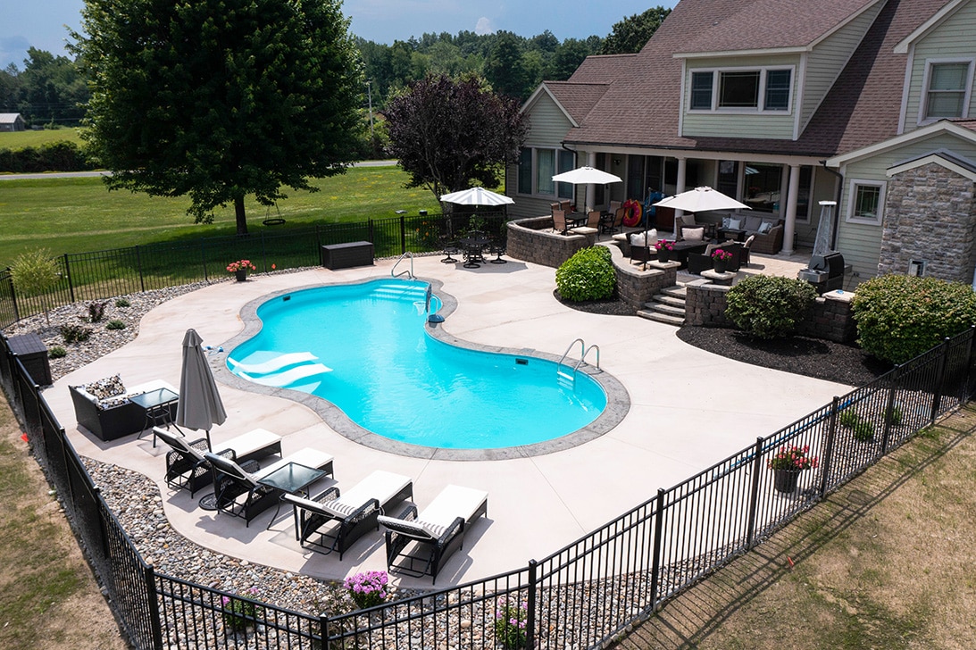 Mountain pond shaped inground pool with sun deck and two lounge chair installed by Cypress Pools